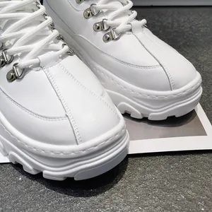 Primo piano di sneaker platform alte bianche con fibbie metalliche e suole chunky