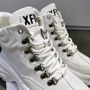 Dettaglio ravvicinato di sneaker alte bianche con ganci in metallo e logo sulla linguetta.