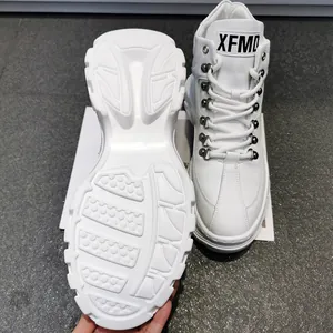 Dettaglio di sneaker alte bianche con suole spesse strutturate e fibbie in metallo.