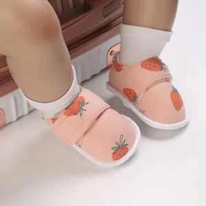 Détail de chaussures de marche pour bébé avec imprimé fraise et velcro