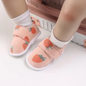 Gros plan sur les chaussures bébé roses avec motifs fraises et fermetures velcro
