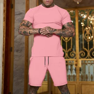 Detail of men's pink short-sleeved sports set on muscular model in luxury setting.