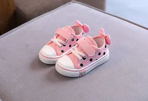Adorable pink polka dot kids canvas shoes featuring a stylish heel bow and soft rubber soles.