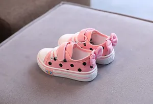 Close-up detail view of pink polka dot canvas baby shoes with bow accent and velcro strap
