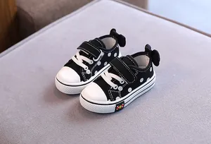 Detailed view of black polka dot toddler canvas shoes featuring a charming bow accent