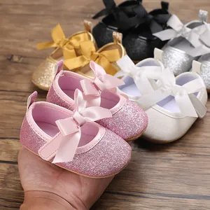 Close-up view of pink glitter baby princess shoes featuring a large satin ribbon bow.