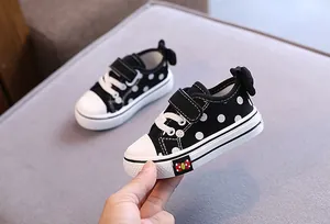 Detail of black polka dot baby girl canvas shoes with bowknot and soft sole.