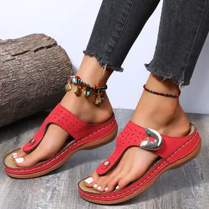 Detailed view of women's red wedge flip-flop sandals featuring decorative metal buckles