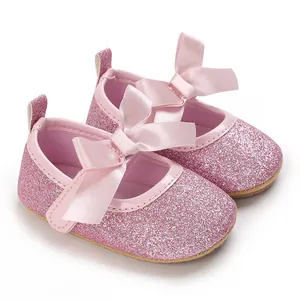 Close-up of pink glitter baby princess shoes featuring satin bows and soft rubber soles