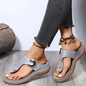 Close-up of grey wedge thong sandals with hollow patterns and buckle detail
