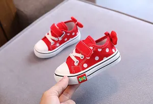 Detailed view of red polka dot toddler canvas shoes featuring a cute bow and velcro strap