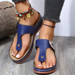 Close-up of blue wedge flip-flop sandals with ornate cutouts and beaded anklets
