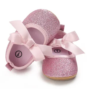 Close-up view of pink glitter baby princess shoes with satin bow and soft rubber sole