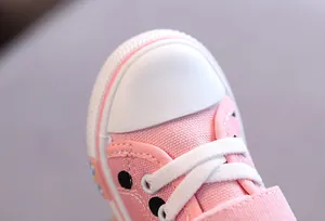 Detailed view of pink toddler canvas shoe showing white rubber toe cap and woven laces