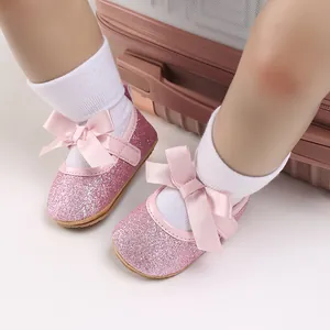 Close-up of pink glitter baby princess shoes with satin bow and soft rubber sole