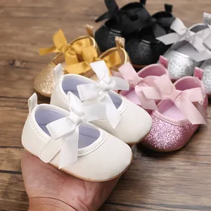 Detailed macro view of glittery baby princess shoes featuring elegant satin bows.
