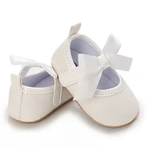 Detailed view of white shimmering baby girl princess shoes with large satin bows