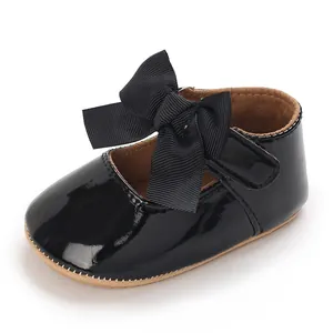 Seitenansicht eines glänzend schwarzen Babyschuhs mit großer Schleife für Mädchen.