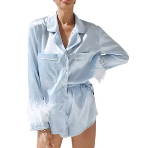 Hellblaues Satin-Pyjama-Set mit weißen Federbündchen an langen Ärmeln und Shorts.