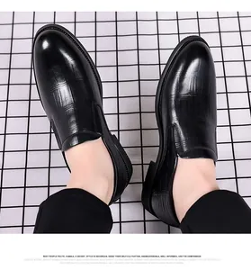 Close-up of black crocodile embossed leather men's dress shoes on a grid background