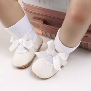 Close-up of white baby girl princess shoes with elegant large satin bows and glitter finish.