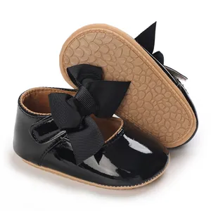 Nahaufnahme schwarzer Lackleder-Babyschuhe für Mädchen mit großer Schleife und weicher Sohle
