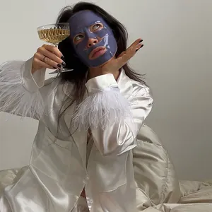 Nahaufnahme von weißem Satin-Pyjama-Set mit luxuriösem Federbesatz an den Ärmeln