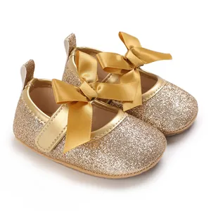 Close-up of gold glitter baby princess shoes with a large satin bow detail.