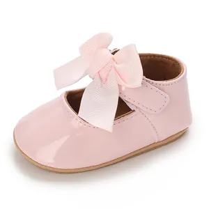 Detailansicht eines rosa Lack-Babyschuhs mit einer großen dekorativen Schleife