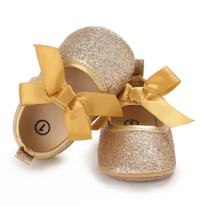 Close-up detail of golden glitter baby princess shoes with satin bow and soft sole