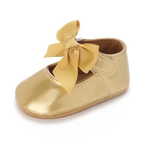 Nahaufnahme goldener Baby-Prinzessinnenschuhe mit großer Schleife und weicher Sohle