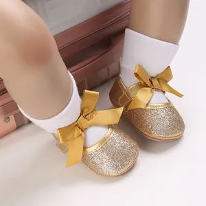 Close-up of golden glitter baby girl princess shoes with soft soles and decorative bows