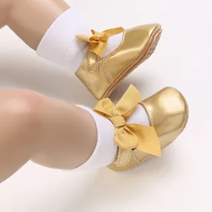 Detailansicht glänzender goldener Babyschuhe für Mädchen mit einer großen dekorativen Schleife