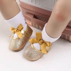 Close-up detail of golden glitter baby girl princess shoes with decorative ribbon bows