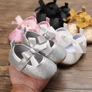 Close-up of sparkling glitter baby princess shoes featuring a satin bow and soft sole