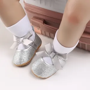 Close-up of silver glitter baby shoes with grey satin bow detail and white socks.