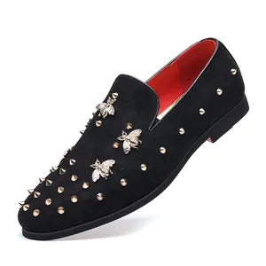 Κοντινό πλάνο σε μαύρα καστόρινα loafers με χρυσή μέλισσα, τρουκς και κόκκινη φόδρα