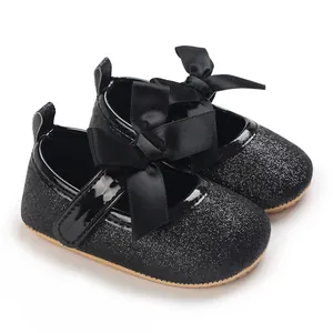 Close-up of elegant black glitter baby girl princess shoes with large satin bows