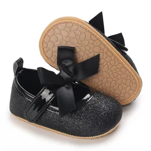 Detailed view of black glitter baby girl princess shoes with a satin bow and soft sole