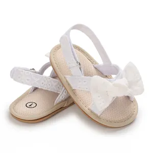 Close-up of white lace baby girl sandals with a decorative bow and soft sole