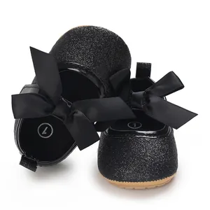 Close-up of black glitter infant baby princess shoes with oversized satin bows detail