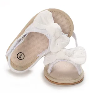 Detailed view of white baby girl walking sandals featuring delicate lace bow design