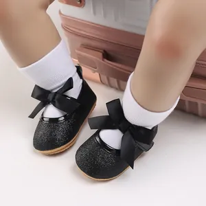 Detail of black glitter baby princess shoes with satin bow and soft non-slip sole.