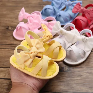 Yellow baby girl sandals with bow decoration and soft textured sole close-up