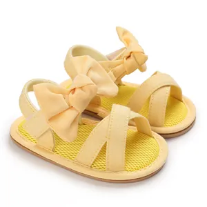 Detailed view of yellow baby girl sandals featuring a large bow and soft rubber sole