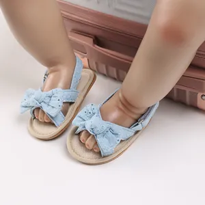 Close-up of blue baby girl sandals with decorative bow and floral lace detail