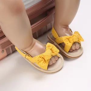 Close-up of yellow baby girl sandals with delicate lace bow decoration and soft sole