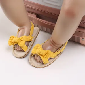 Detailed view of yellow baby girl sandals with decorative bow and breathable fabric