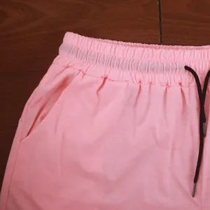 Close-up of the elastic waistband and black drawstring on pink sports shorts.