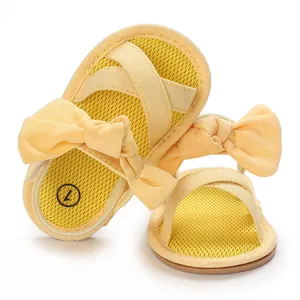 Macro view of yellow infant walking sandals featuring cute bow and soft gum sole